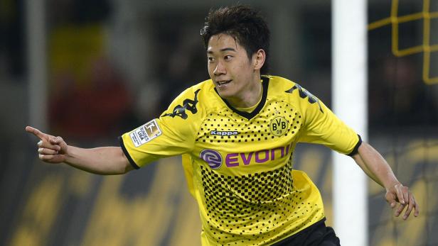 Shinji Kagawa im gelben Trikot von Borussia Dortmund zeigt mit dem Finger.