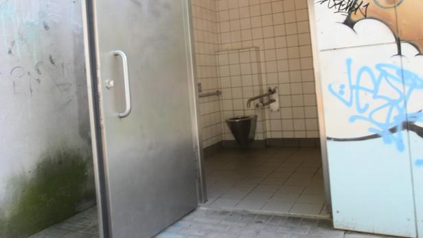 Ein Blick in eine öffentliche Toilette mit Graffiti an den Wänden.
