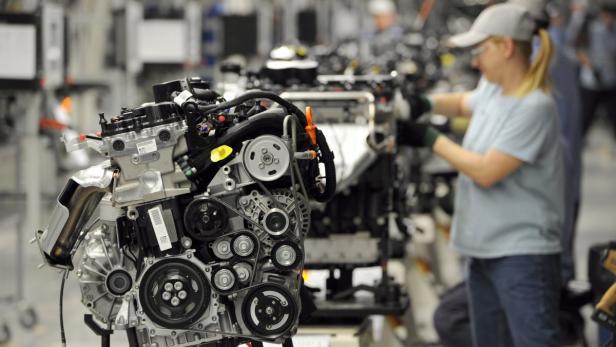 Eine Frau arbeitet an einem Automotor in einer Fabrik.