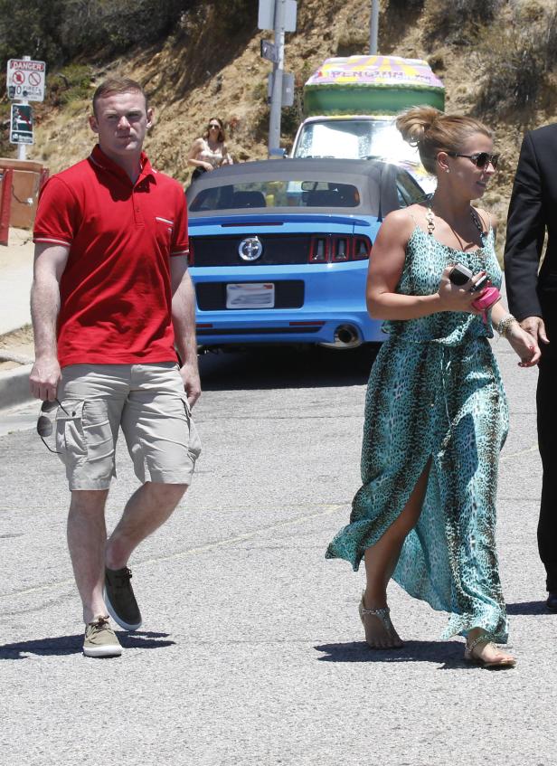 Wayne Rooney und seine Frau Coleen spazieren auf einer sonnigen Straße.