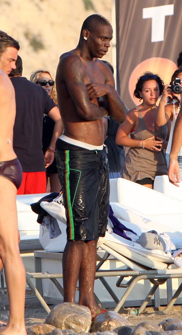 Mario Balotelli steht am Strand, umgeben von anderen Personen.