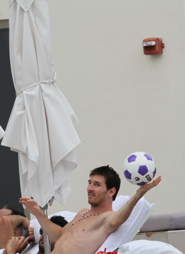 Lionel Messi entspannt am Pool und balanciert einen Fußball.