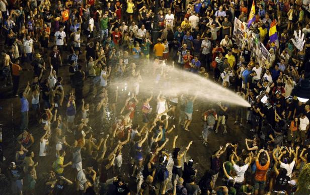 Bei einer Demonstration werden Menschen mit einem Wasserwerfer bespritzt.