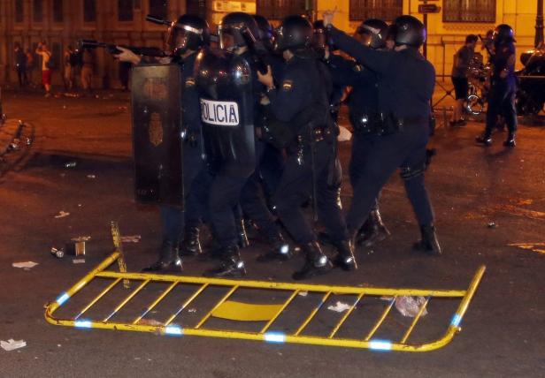 Eine Reihe von Polizisten mit Schutzschilden und Waffen steht auf einer Straße.