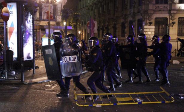 Eine Reihe von Polizisten mit Schutzschilden steht auf einer Straße.