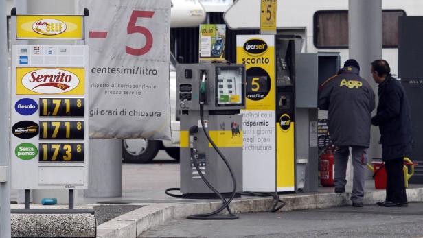 Eine Agip-Tankstelle mit Preisanzeige und zwei Personen im Gespräch.