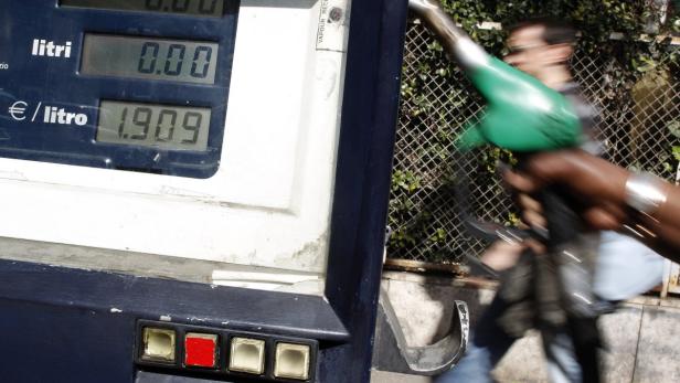 Eine Zapfsäule zeigt einen Preis von 1,909 Euro pro Liter an, während jemand im Hintergrund tankt.