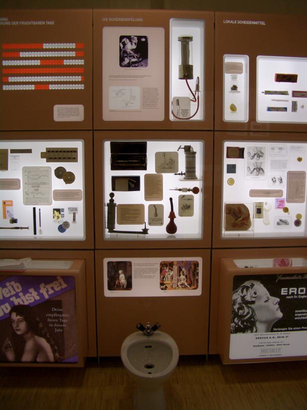 Eine Ausstellung über Verhütungsmethoden mit historischen Geräten und Werbeplakaten.