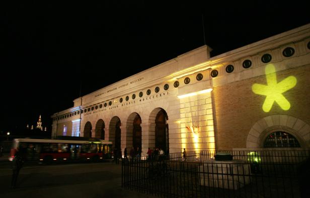 Das Burgtor in Wien ist nachts beleuchtet, mit einem gelben Stern an der Fassade.