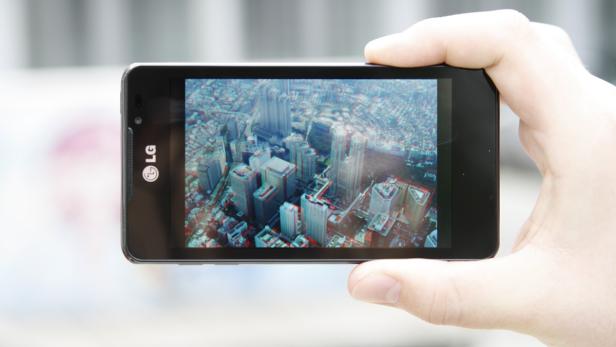 Eine Hand hält ein LG-Smartphone, das eine 3D-Ansicht einer Stadt zeigt.