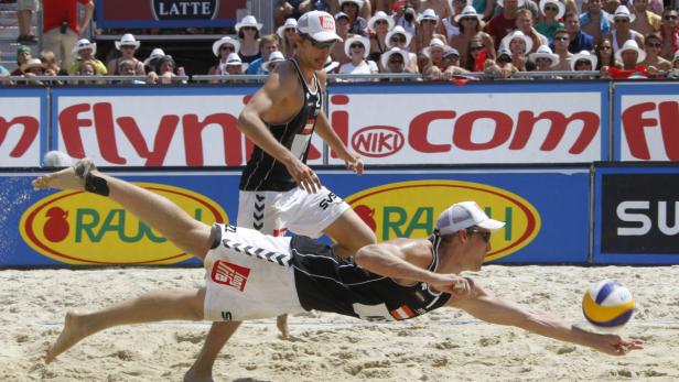 Ein Beachvolleyballspieler hechtet nach dem Ball vor einer Zuschauermenge.