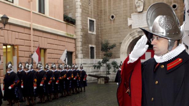 Ein Mitglied der Schweizergarde salutiert vor einer Reihe von Gardisten.