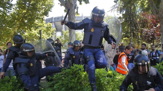 Polizisten in voller Montur stehen während einer Demonstration im Einsatz.