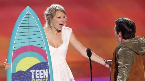Taylor Swift nimmt bei den Teen Choice Awards einen Preis in Form eines Surfbretts entgegen.