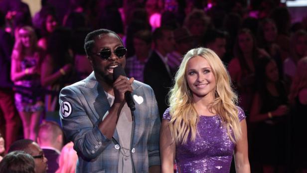 Will.i.am und Hayden Panettiere stehen auf einer Bühne vor Publikum.