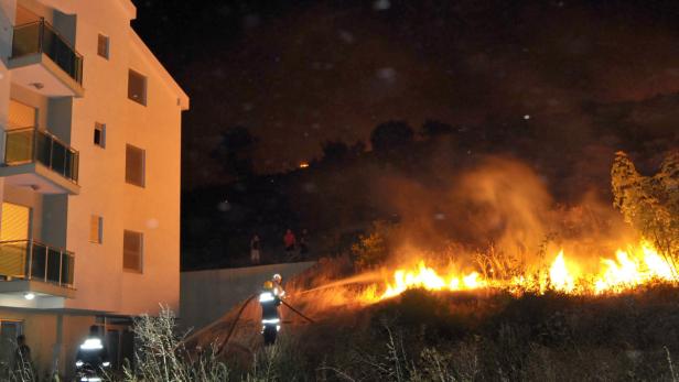 Ein Feuerwehrmann löscht einen Brand in der Nähe eines Wohnhauses.