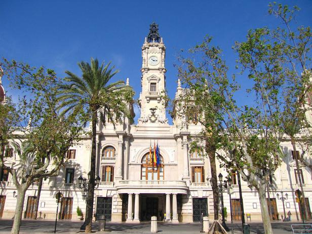 Das Rathaus von Valencia, ein großes, verziertes Gebäude mit einem Uhrturm, unter blauem Himmel.