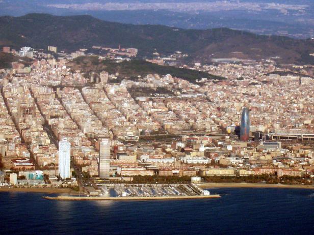 Luftaufnahme von Barcelona mit dem markanten Torre Glòries und Blick auf das Meer.