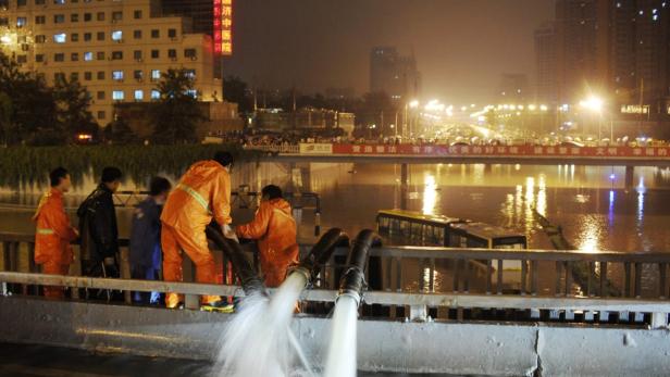 Arbeiter pumpen Wasser aus einem überfluteten Gebiet in einer Stadt.