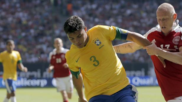 Ein brasilianischer Fußballspieler im Zweikampf mit einem dänischen Spieler.