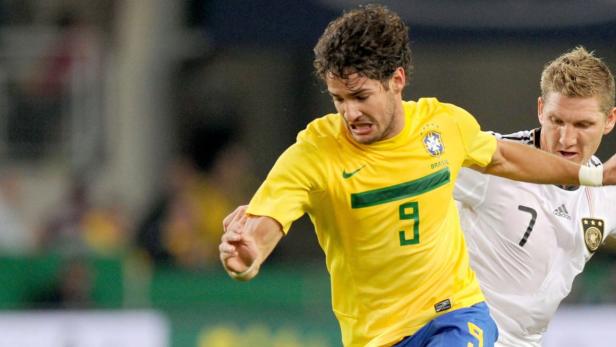 Zwei Fußballspieler, einer im gelben Trikot Brasiliens, kämpfen um den Ball.