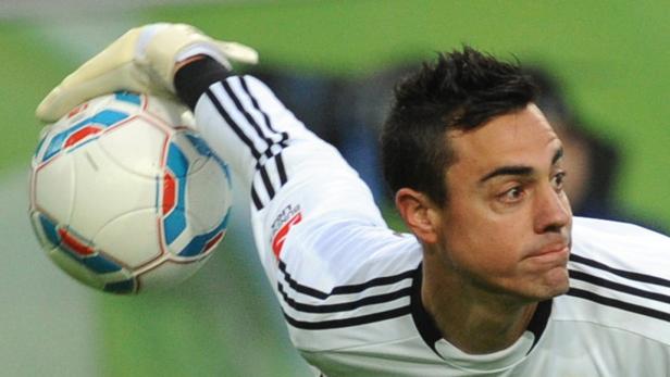 Ein Torwart fängt einen Fußball mit der Hand.