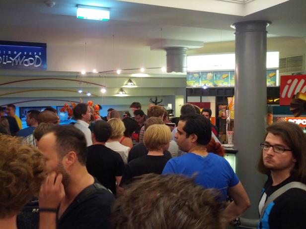 Eine Menschenmenge steht in der Schlange vor einem Kino-Café namens „Hollywood“.