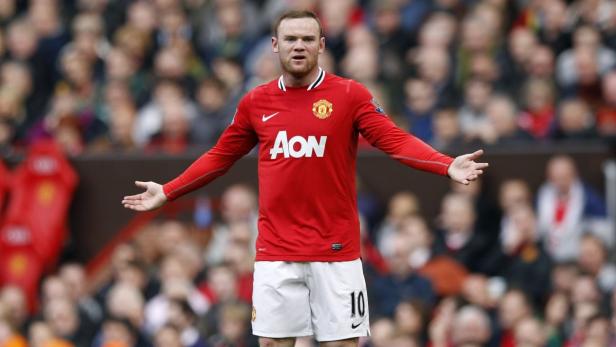 Wayne Rooney im Trikot von Manchester United mit ausgestreckten Armen vor einer Zuschauermenge.