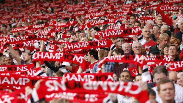 Eine große Menschenmenge schwenkt rote Schals mit der Aufschrift „Champions“.