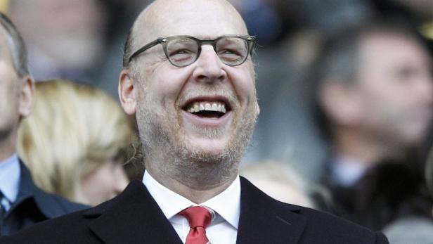 Ein lachender Mann mit Brille und Anzug im Publikum.