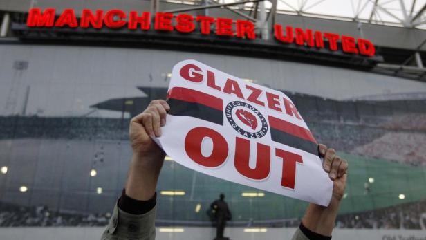 Ein Transparent mit der Aufschrift „Glazer Out“ wird vor dem Manchester United Stadion hochgehalten.