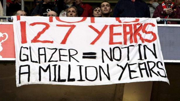 Ein Transparent mit der Aufschrift „127 Years Glazer = Not in a Million Years“ wird von Zuschauern gehalten.