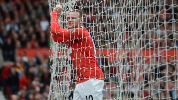 Wayne Rooney hängt im Netz eines Fußballtors.