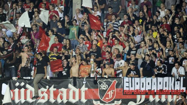 Eine Menschenmenge jubelt auf der Tribüne bei einem Fußballspiel.