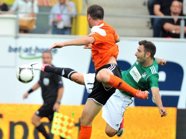 Zwei Fußballspieler kämpfen um den Ball während eines Spiels.