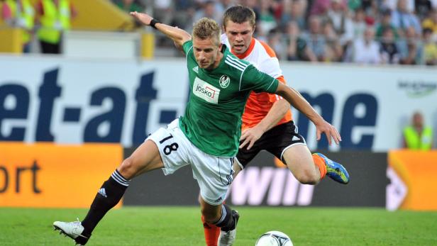 Zwei Fußballspieler kämpfen um den Ball auf dem Spielfeld.