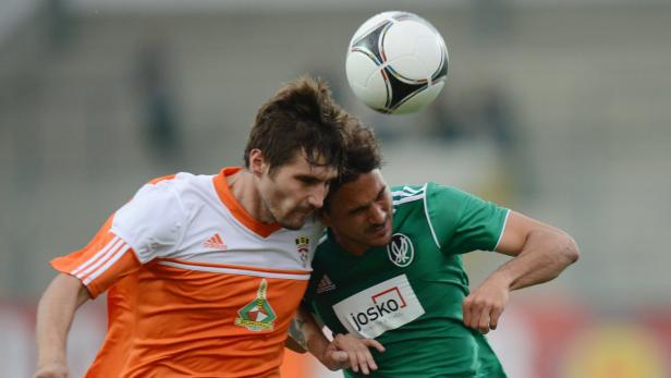 Zwei Fußballspieler kämpfen um den Ball während eines Spiels.