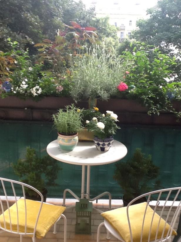 Ein kleiner Balkon mit einem Tisch, Stühlen und vielen Pflanzen.