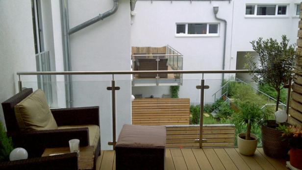 Einrichtung auf einem Balkon mit Korbsessel und Pflanzen.