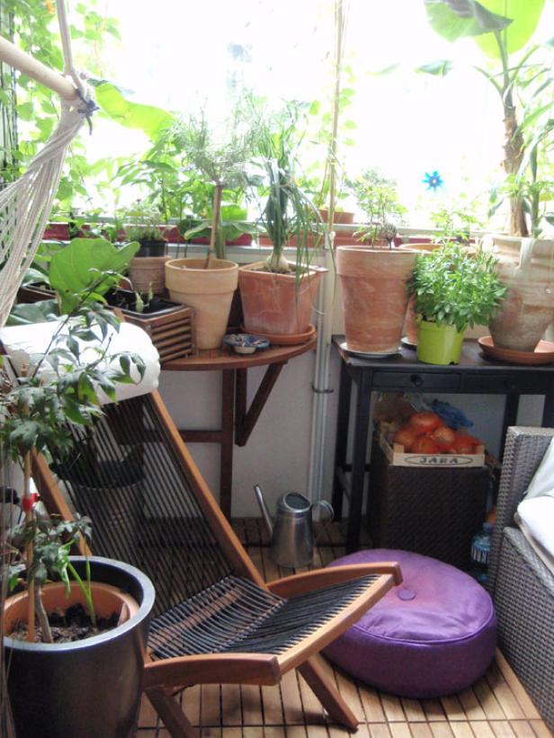 Ein bepflanzter Balkon mit einem Liegestuhl und verschiedenen Pflanzen in Töpfen.