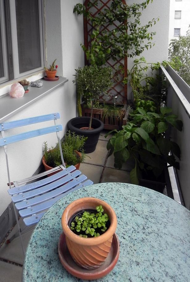 Ein kleiner Stadtbalkon mit Tisch, Stuhl und verschiedenen Topfpflanzen.