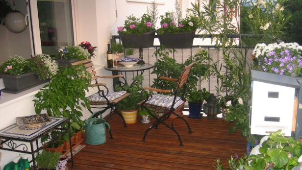 Ein mit Pflanzen und Möbeln dekorierter Balkon mit Holzboden.