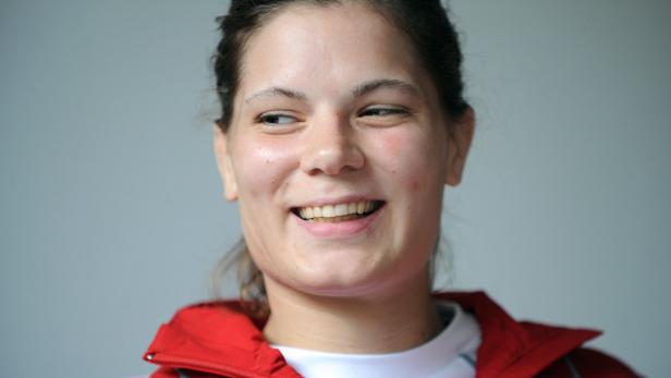 Eine lächelnde Frau mit roter Jacke blickt zur Seite.