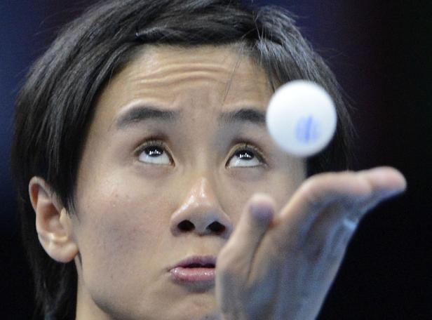 Ein Tischtennisspieler blickt auf einen Ball, den er in die Luft wirft.