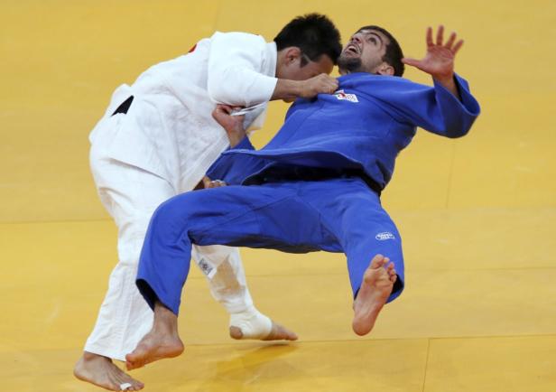 Ein Judoka im weißen Anzug wirft einen Judoka im blauen Anzug zu Boden.