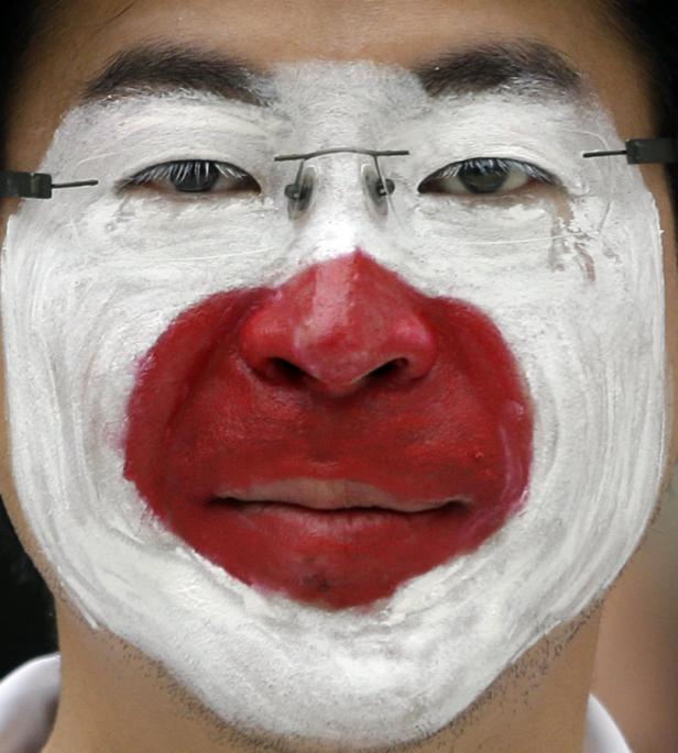 Ein Mann hat sein Gesicht mit der japanischen Flagge bemalt.