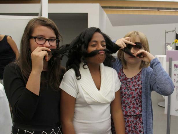 Drei Mädchen posieren mit ihren Haaren als falsche Schnurrbärte.