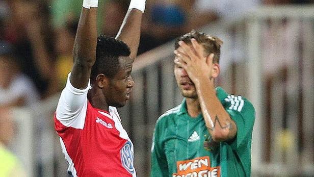 Ein Fußballspieler jubelt, während ein anderer enttäuscht sein Gesicht verdeckt.