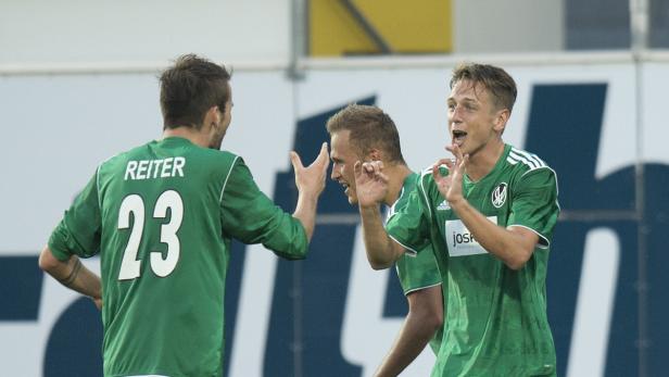 Fußballspieler in grünen Trikots feiern ein Tor.