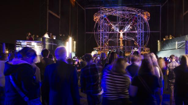 Eine Menschenmenge beobachtet eine Tesla-Spule, die Blitze erzeugt.